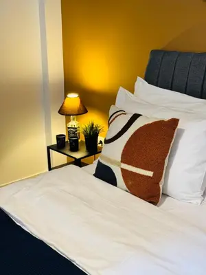 a bed with white sheets and a pillow on it at Mosaic Apartment in Athens