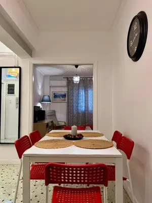 a dining room table with red chairs and a clock at Mosaic Apartment in Athens