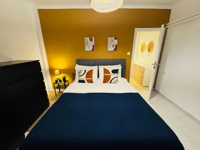 a bedroom with a large bed and a yellow wall at Mosaic Apartment in Athens