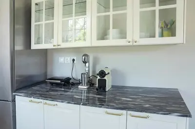 a kitchen with white cabinets and a black counter top at Comfortable Villa - 2min from the Beach in Porto Rafti