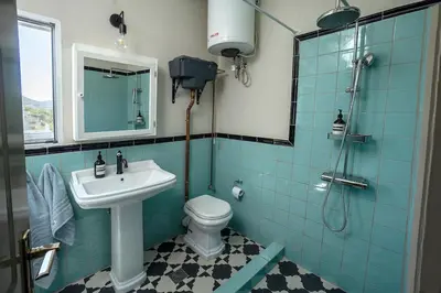 a blue tiled bathroom with a sink and a toilet at Comfortable Villa - 2min from the Beach in Porto Rafti
