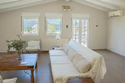 a living room with a white couch and a table at Comfortable Villa - 2min from the Beach in Porto Rafti