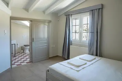 a bedroom with a bed and a bathroom with a toilet at Comfortable Villa - 2min from the Beach in Porto Rafti