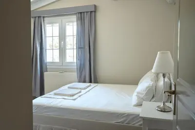 a bedroom with a white bed and a window at Comfortable Villa - 2min from the Beach in Porto Rafti