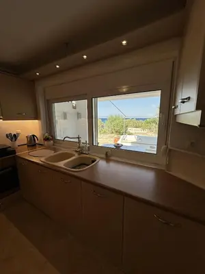 a kitchen with a sink and a large window at Orris Seaside in Vaia