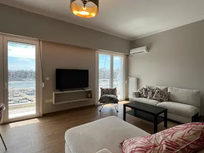 a living room with a couch and a flat screen tv at Piraeus Pearl - Seaview Elegance in Piraeus
