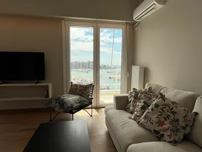 a living room with a couch and a large window at Piraeus Pearl - Seaview Elegance in Piraeus