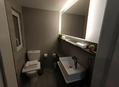 a bathroom with a sink and a toilet and a mirror at Cozy City Hideaway in Zografou in Athens