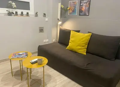 a black couch with a yellow pillow and a table at Cozy City Hideaway in Zografou in Athens