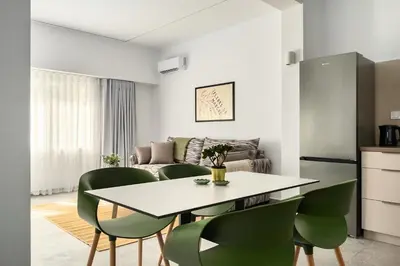 a kitchen and living room with a table and green chairs at The Magnificent Exarchia Loft Apartments in Athens