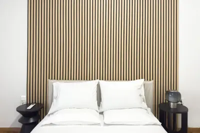 a bed with white pillows in front of a striped wall at Casa Bianca in Pagrati in Athens