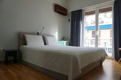 a bedroom with a bed and a large window at Sharing can change the world! in Athens