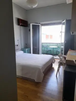 a bedroom with a white bed and a balcony at Sharing can change the world! in Athens