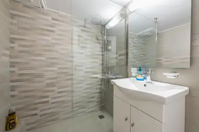 a bathroom with a sink and a glass shower at Heart of Athens Stay Apartment in Athens