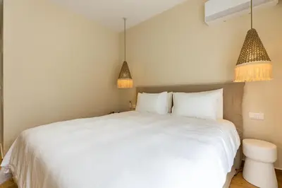 a bedroom with a white bed and two pendant lights at The Sea Breeze, Glyfada in Athens