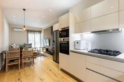 a kitchen with white cabinets and a dining room at The Sea Breeze, Glyfada in Athens