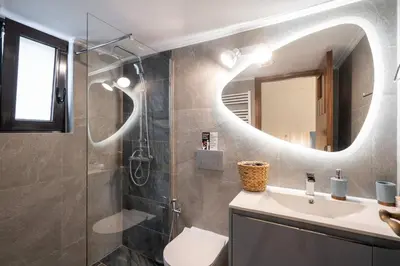 a bathroom with a shower and a sink and a mirror at 3BR Private House with 3 Bathrooms & Amazing Balcony in Athens
