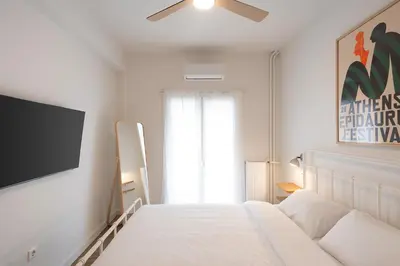 a white bedroom with a bed and a flat screen tv at 1BR Designer Apt Next To Metro & 15 minutes to Acropolis in Athens