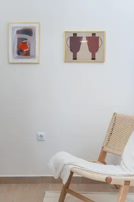 a white room with a chair and two paintings at 1BR Cozy Apt Near Metro with Huge Balcony &City View in Athens