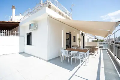 a white house with a table and chairs on a balcony at 1BR Cozy Apt Near Metro with Huge Balcony &City View in Athens