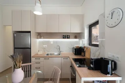 a kitchen with white cabinets and a clock on the wall at 1BR Cozy Apt Near Metro with Huge Balcony &City View in Athens