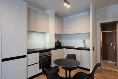 a kitchen with white cabinets and a table and chairs at 2BR Apartment, Access to Rooftop Retreat with Sauna & Jacuzzi in Athens