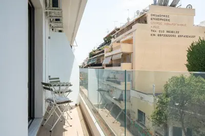 a balcony with a chair and a building at 2BR Apartment, Access to Rooftop Retreat with Sauna & Jacuzzi in Athens