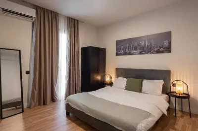 a bedroom with a bed and two lamps and a window at 2BR Apartment, Access to Rooftop Retreat with Sauna & Jacuzzi in Athens