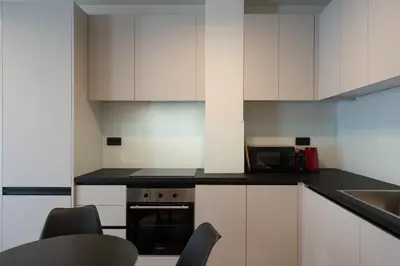 a kitchen with white cabinets and a stove top oven at 2BR Apartment, Access to Rooftop Retreat with Sauna & Jacuzzi in Athens