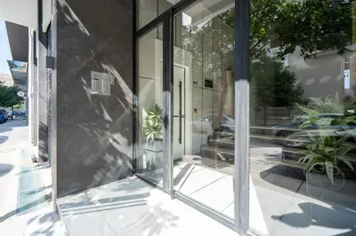 a glass facade of a building with potted plants at Modern 2BR with Rooftop Jacuzzi & Sauna Access in Athens