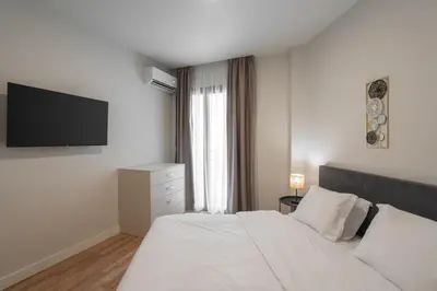 a bedroom with a white bed and a television at Modern 2BR with Rooftop Jacuzzi & Sauna Access in Athens