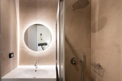 a bathroom with a sink and a shower with a mirror at Modern 2BR with Rooftop Jacuzzi & Sauna Access in Athens
