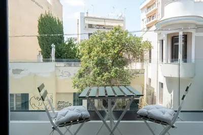 a table and two chairs on a balcony with a tree at Modern 2BR with Rooftop Jacuzzi & Sauna Access in Athens
