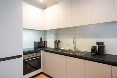 a kitchen with white cabinets and a sink at Stylish 2BR Apt, Rooftop with Sauna & Hot Tub in Athens