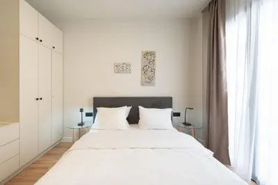 a white bedroom with a large bed and a window at Stylish 2BR Apt, Rooftop with Sauna & Hot Tub in Athens