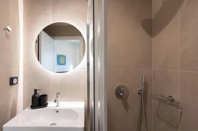 a bathroom with a sink and a shower with a mirror at Stylish 2BR Apt, Rooftop with Sauna & Hot Tub in Athens