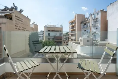 a table and chairs on a balcony with a view of buildings at 2BR Apt Access To Rooftop with Sauna & Jacuzzi in Athens