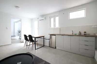 a kitchen with white cabinets and a table and chairs at Muse Studios & Apartments in Agia Marina Aegina