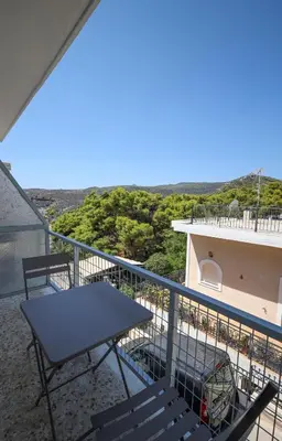a table and chairs on the balcony of a house at Muse Studios & Apartments in Agia Marina Aegina