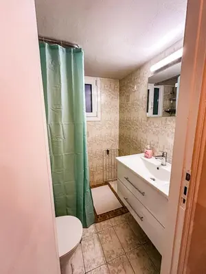 a bathroom with a green shower curtain and a sink at The North Nest in Athens