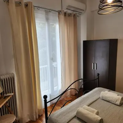 a bedroom with a bed and a large window at Athens Nest one in Athens