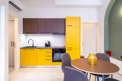 a kitchen with yellow cabinets and a table and chairs at Pasalimani Seabreeze Apartment in Piraeus