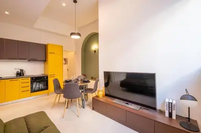 a living room with a large television and a kitchen at Pasalimani Seabreeze Apartment in Piraeus