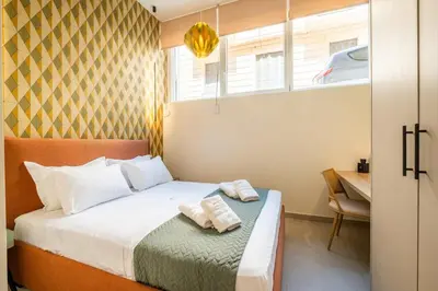 a bedroom with a bed and a table and a window at Pasalimani Seaside Apartment in Piraeus