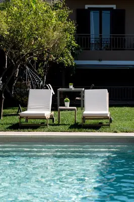 two white chairs sitting next to a swimming pool at Olivea Residence by A&D Properties in Porto Rafti