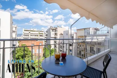 a table on a balcony with a view of buildings at Comfortable & Modern Apt 4floor 3ppl in Piraeus