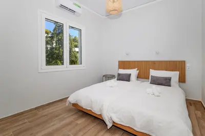 a white bedroom with a large bed with two pillows at Muse Studios & Apartments Aegina in Agia Marina Aegina