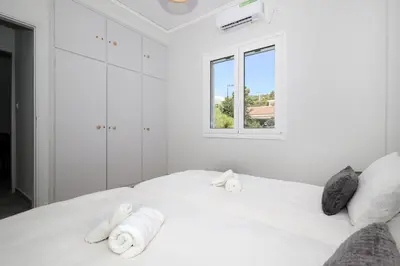 a white bedroom with a bed with towels on it at Muse Studios & Apartments Aegina in Agia Marina Aegina