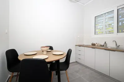 a kitchen with a wooden table and black chairs at Muse Studios & Apartments Aegina in Agia Marina Aegina