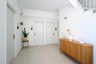 a hallway with white walls and a wooden cabinet at Muse Studios & Apartments Aegina in Agia Marina Aegina